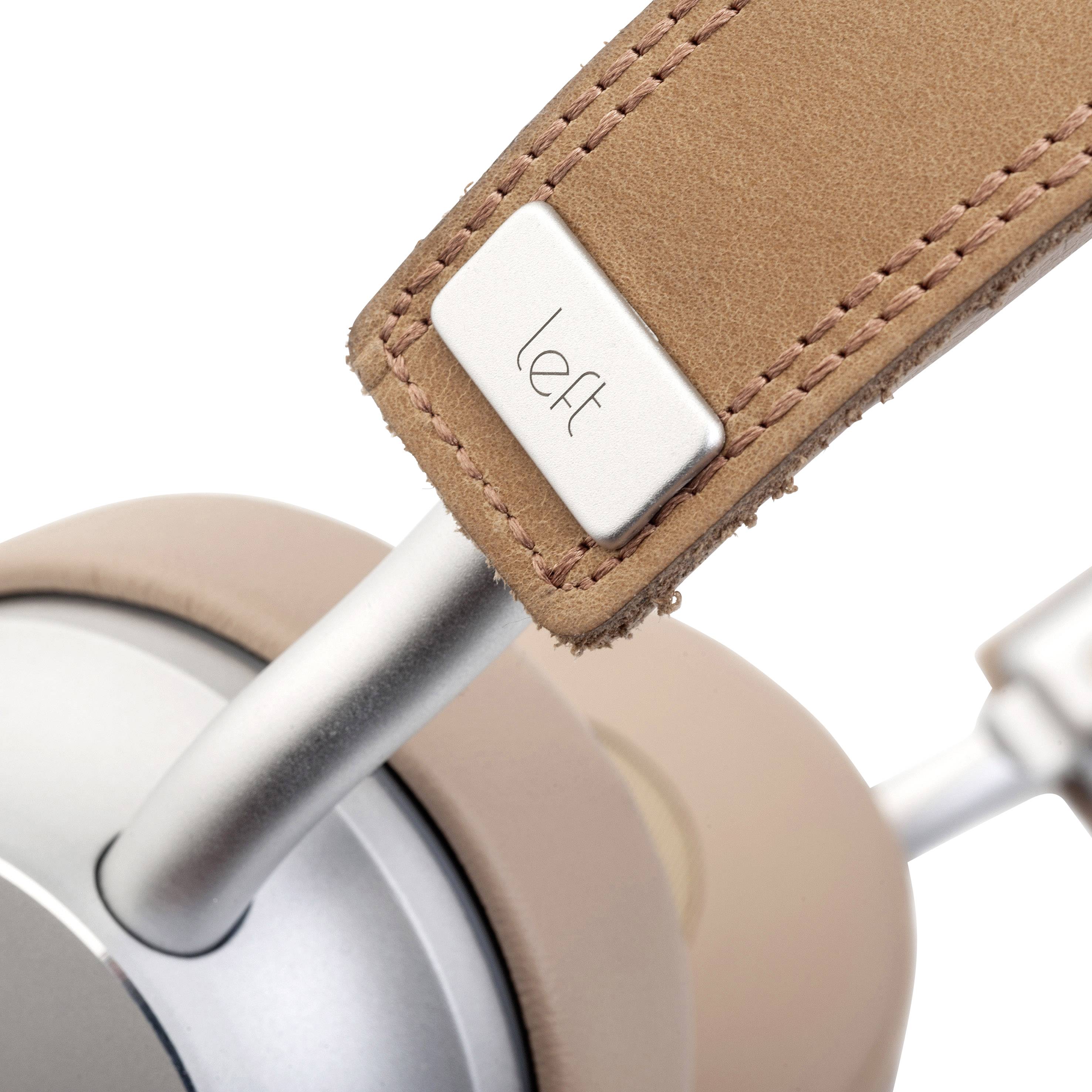 Close-up of a headphone with a beige-coloured headband and metal structure. A small plate shows the inscription 'left'.