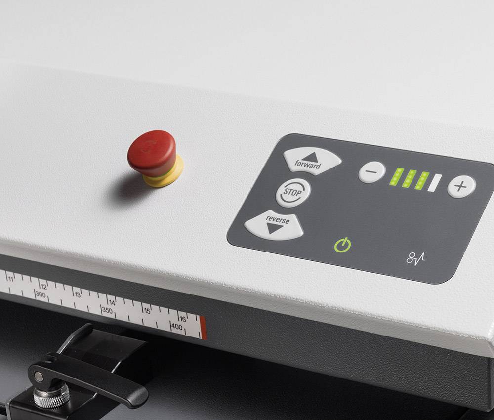 Control panel of a machine with a red emergency stop button, buttons for forward, reverse, and stop functions, along with a power indicator.