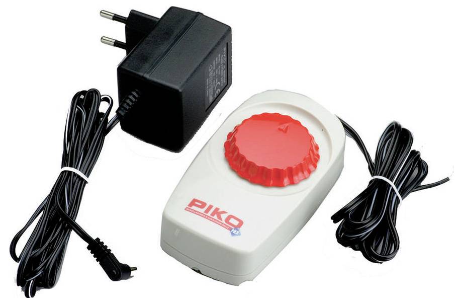 Power supply unit and PIKO rotary controller for controlling model railways. On the left, a black power supply unit; on the right, the white controller with a red knob.
