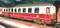 A red train carriage stands in a covered railway station. Some windows are open. The carriage has the inscription 'Deutsche Bahn'.