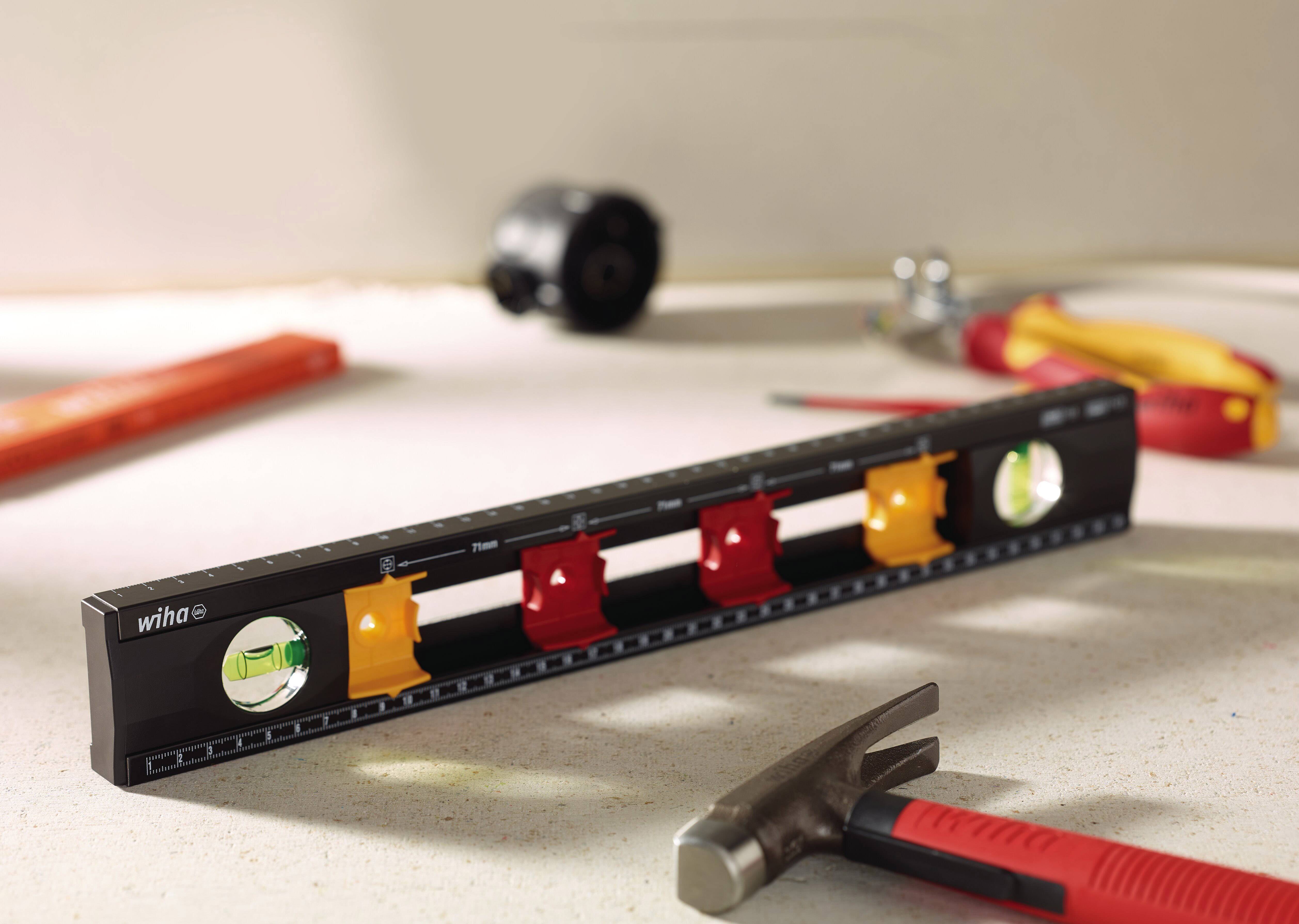 Spirit level with multiple vials, tools in the background. Primarily used for precise alignment of surfaces.