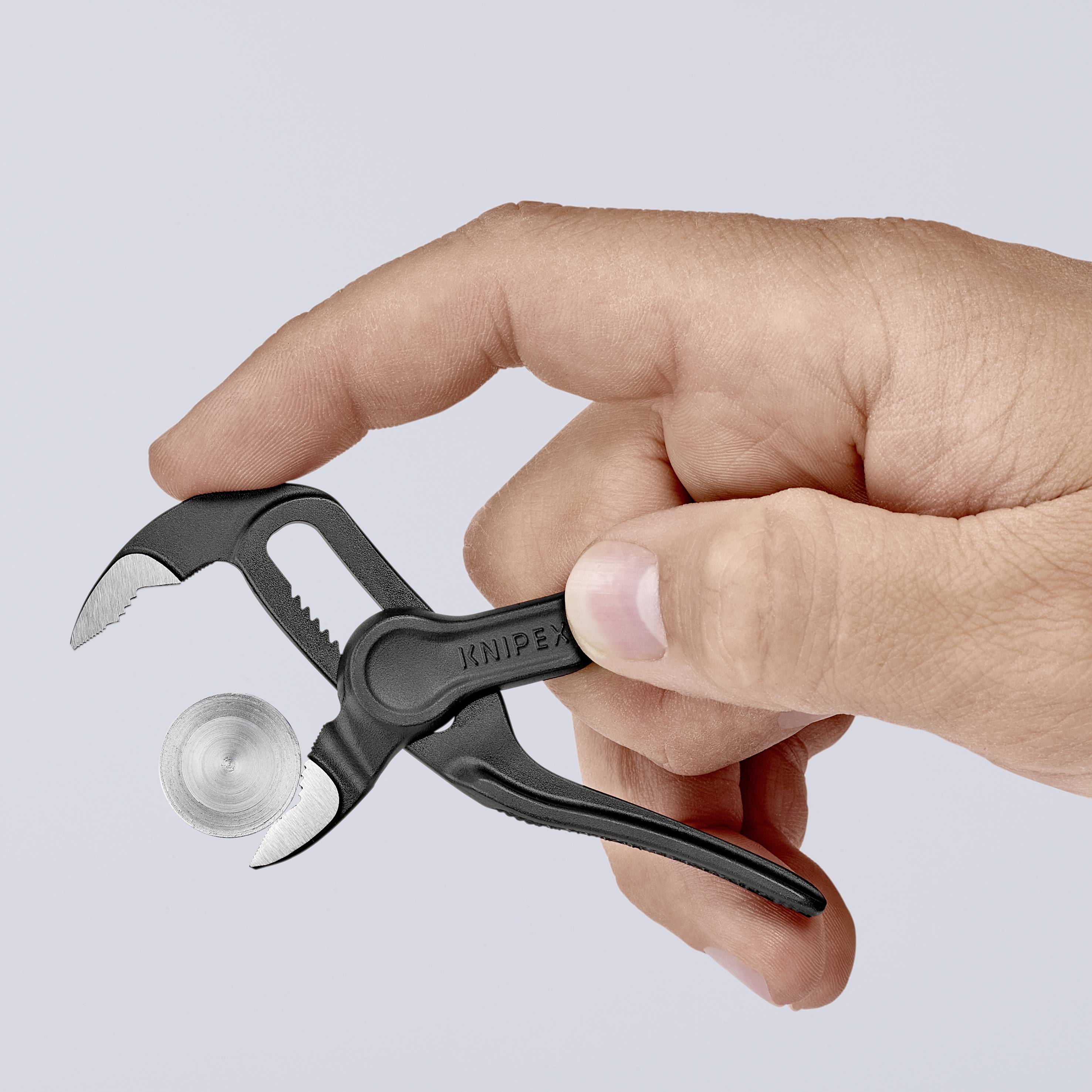 A hand is holding a small pair of pliers, brand KNIPEX, gripping a coin.