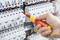 A hand is working with an isolated screwdriver on a fuse box to check or adjust electrical circuits.