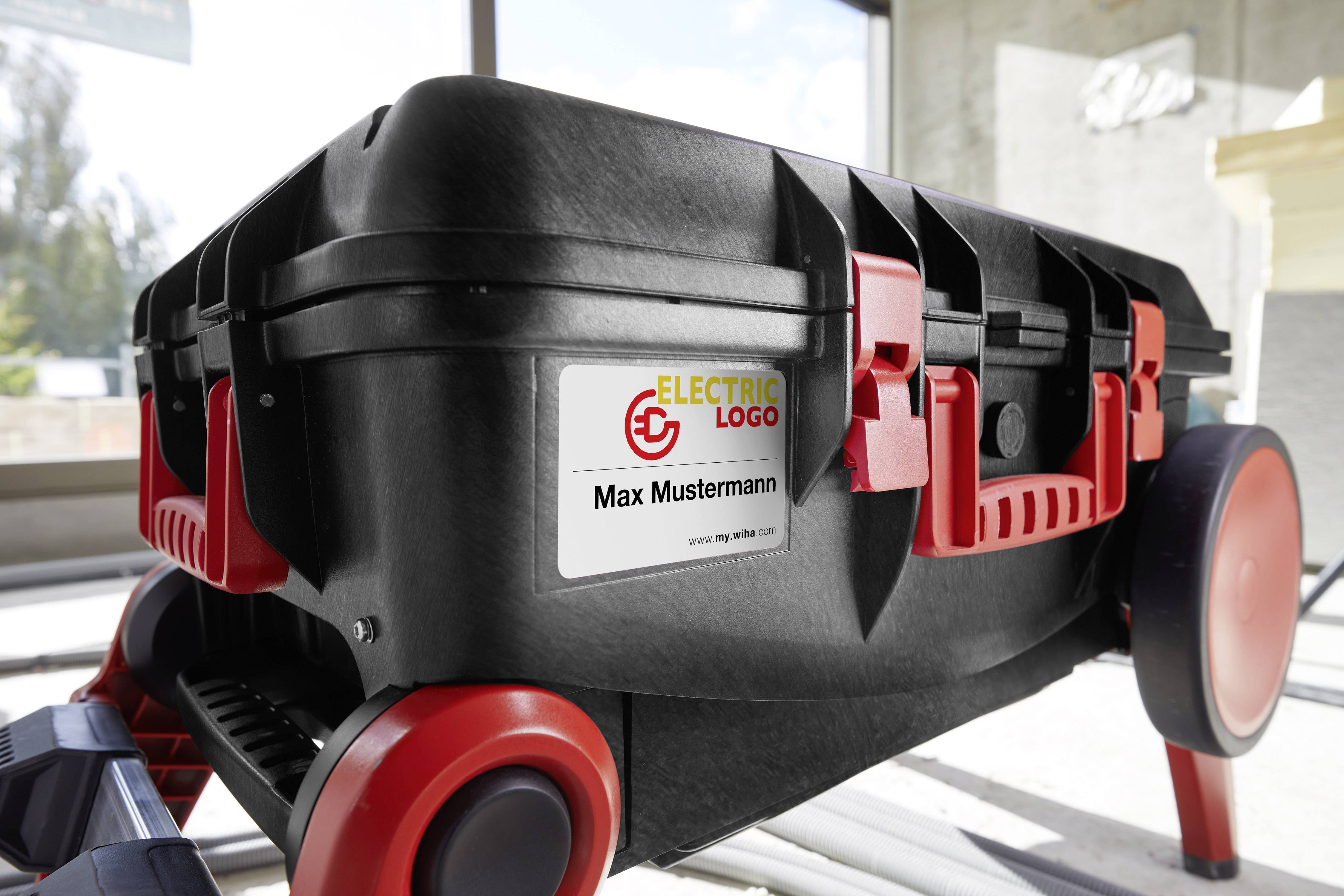 Black tool case with red wheels and latches. Sticker with the inscription 'Max Mustermann' and 'ELECTRIC LOGO'.