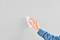 A hand wipes a grey wall clean with a white cloth. The person is wearing a blue shirt.