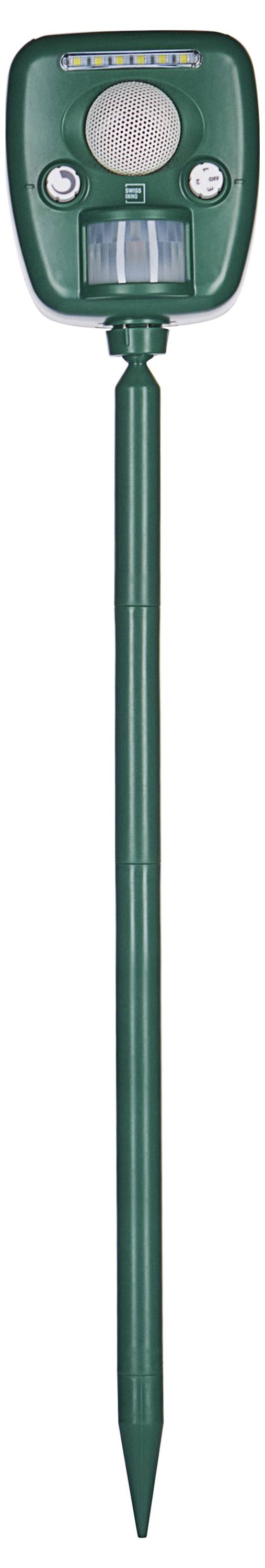 A green outdoor pest repeller with a pointed stake, solar panel on top, sensor in front, and adjustment knobs visible for settings control.