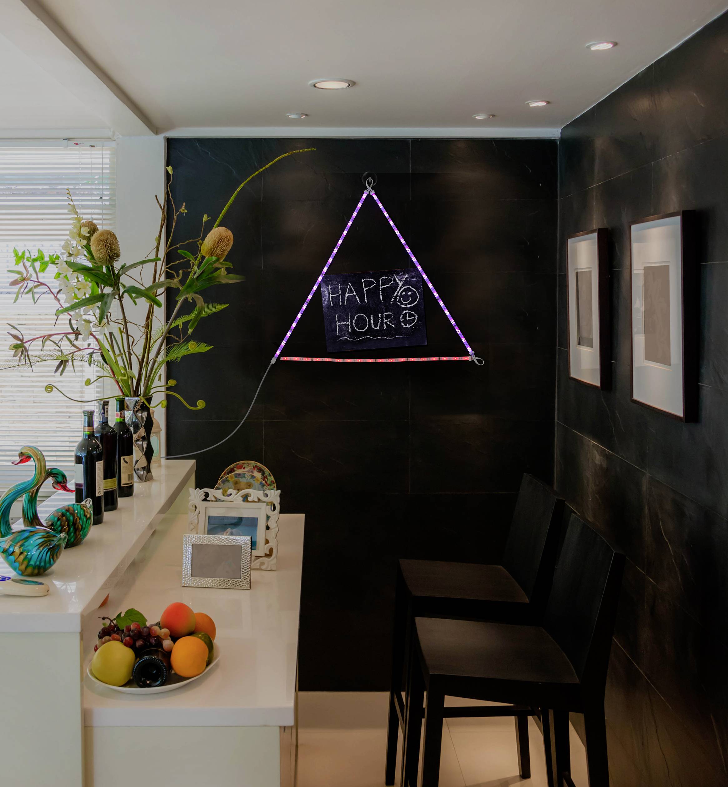 A cosy room with a bar counter, decorated with bottles and fruit. A sign reading 'Happy Hour' hangs on the wall.