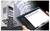 A person is holding a tablet with software for monitoring machines. Next to the tablet is an electrical control box and a QR code.