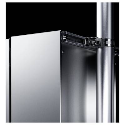 A silver, metallic cabinet stands next to a vertical pipe, with technical connections between the two elements.