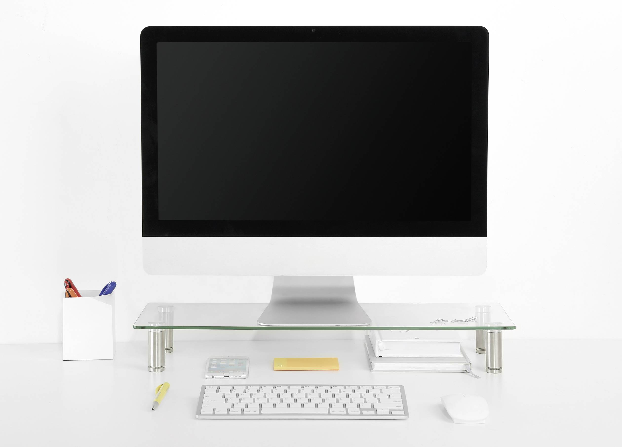 A tidy, well-organised desk with a computer monitor, keyboard, mouse and several writing implements in a container.