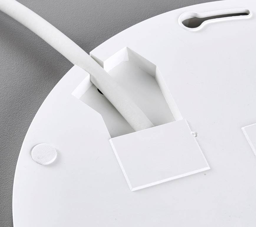 A white cable is pulled through an opening in a white, round plastic casing with a smooth surface.