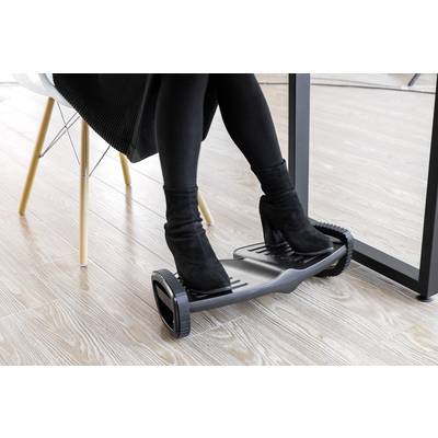 A person wearing black boots is using an office fitness device under a desk to move their feet while seated.