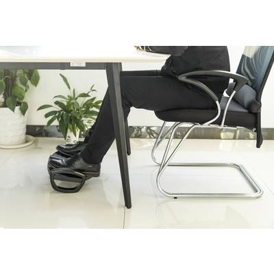 A person is seated in an office chair at a desk, their feet resting on a footrest. A plant stands in the background.