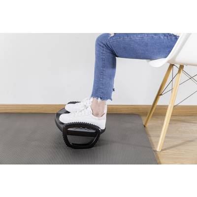 A person wearing jeans and white trainers is using a footrest while sitting on a white chair.