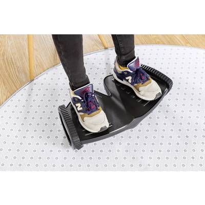 Someone is standing in trainers on a black balance training device on a dotted carpet floor.