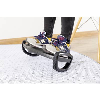 A person is standing on a self-balancing, unicycle-like device with two large tyres. They are wearing trainers. The floor is covered with a patterned carpet.