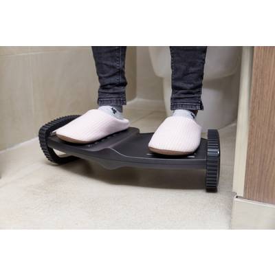 Feet in pink slippers stand on an adjustable footrest beside a toilet.