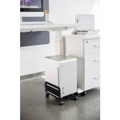 A modern, white computer sits on a trolley beneath a white desk next to a white chest of drawers with books.