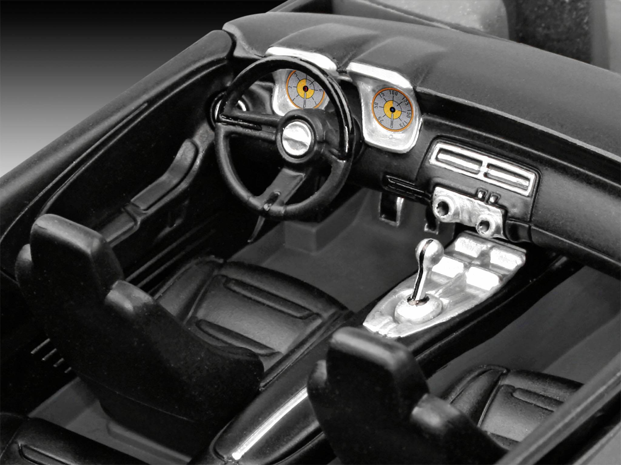 Interior of a model car with steering wheel, gear stick, and dashboard.