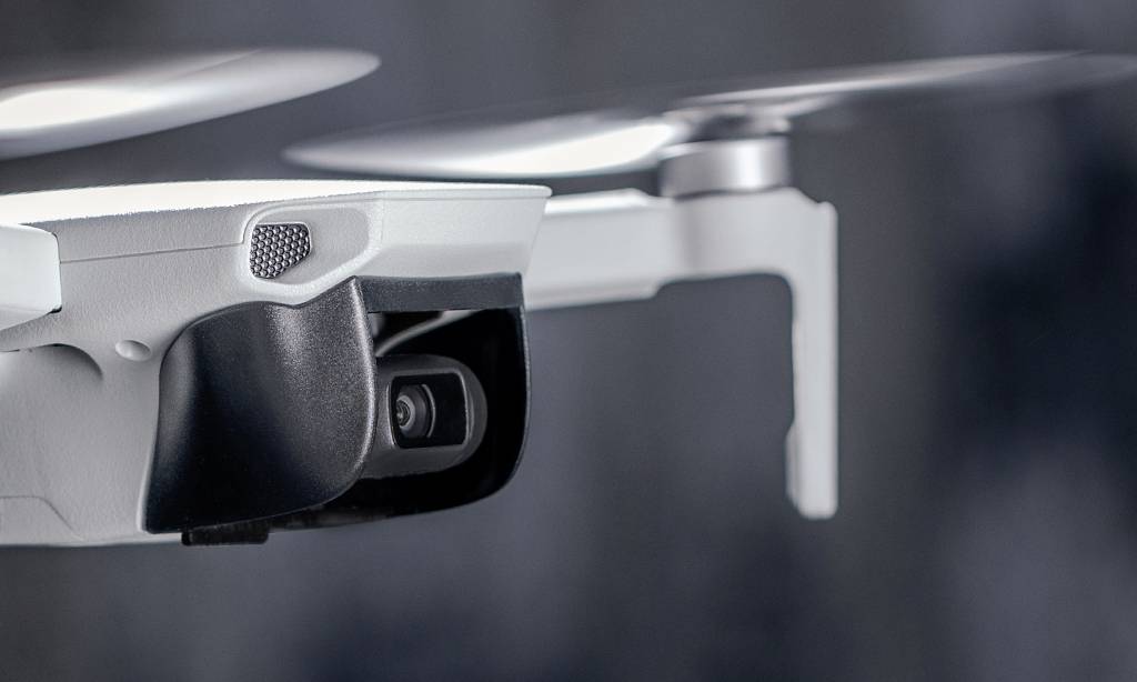 Close-up of a drone with a camera in motion. The propellers are blurred, indicating activity.