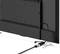 Rear view of a television with an HDMI cable plugged into a port on the side. The device is standing on silver feet.