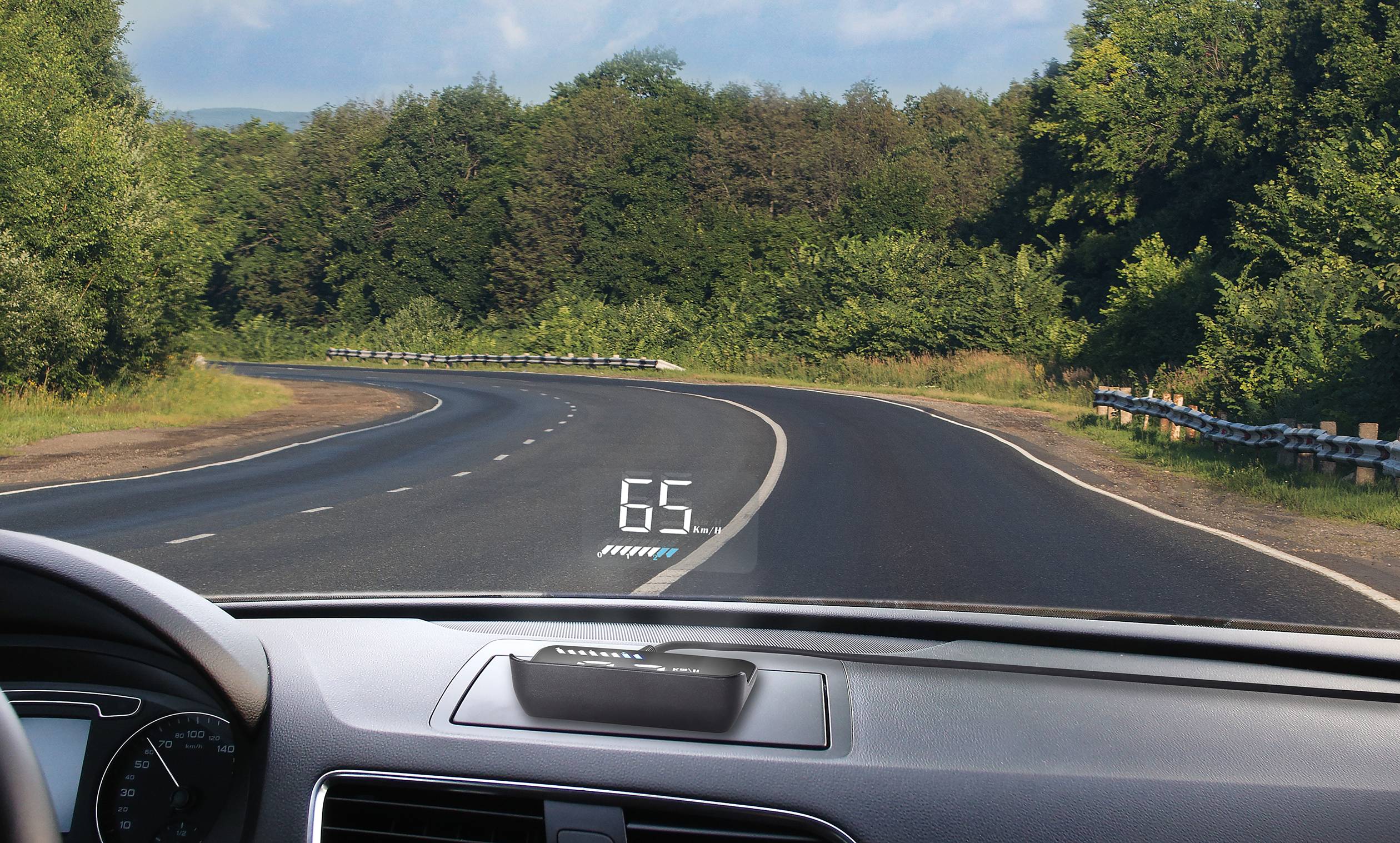 Road through woodland from a vehicle's perspective; speed display ('65') projected on windscreen.