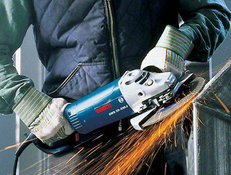 A person is using an angle grinder, generating sparks while working on metal. The person is wearing protective clothing.