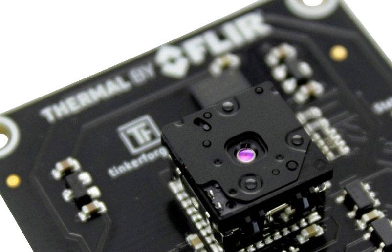 Close-up of a thermal imaging camera from above, showing the central lens and surrounding circuitry on a circuit board.