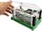 A hand lifts the transparent lid of an electrical control box filled with circuits and connections.