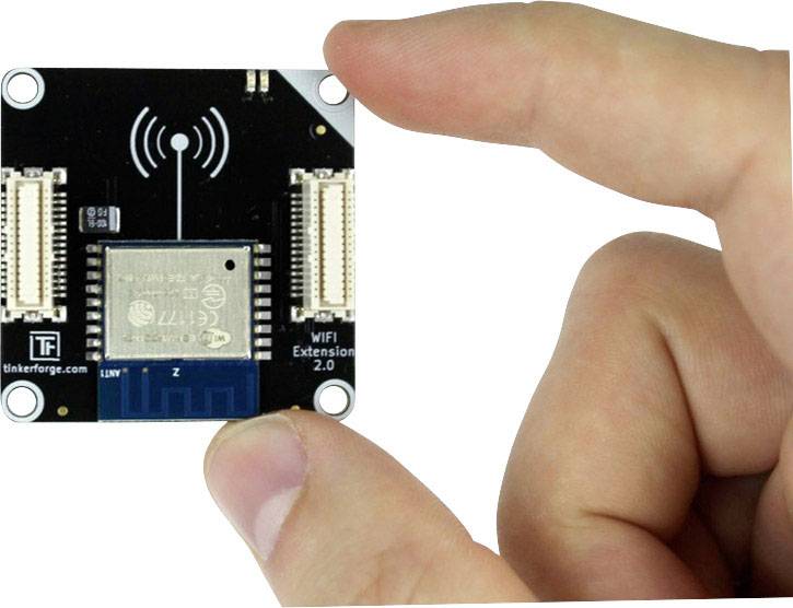 A hand is holding a small electronic module printed with 'WiFi Extension 2.0'. A WiFi symbol is visible on the top of the circuit board.