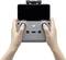 Two hands are holding a grey remote control with a mounted smartphone, used for controlling drones.