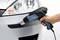 A hand holds a hot air blower near a car to shape a plastic bumper.