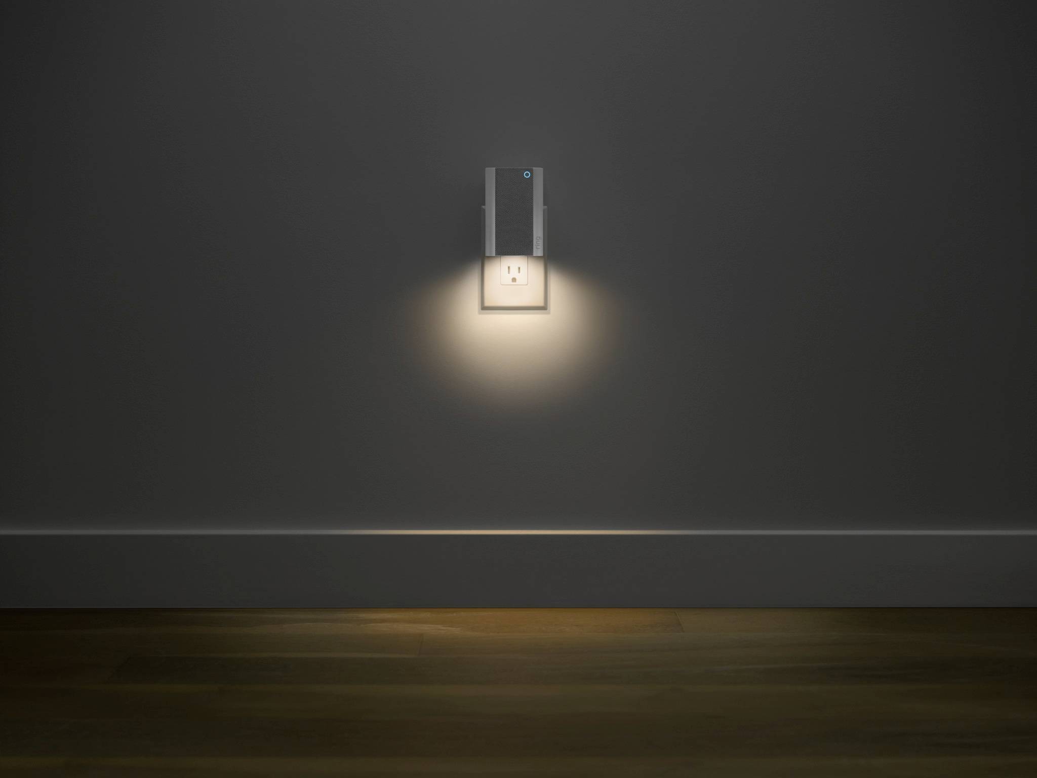 Electrical socket with night light in a dark room; gently illuminates the floor area beneath it.