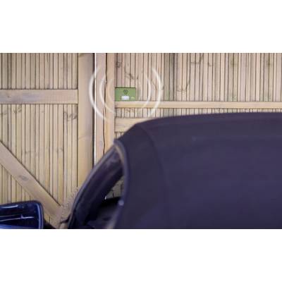 A car is parked in front of a closed wooden gate. A green sign displays a Wi-Fi signal.