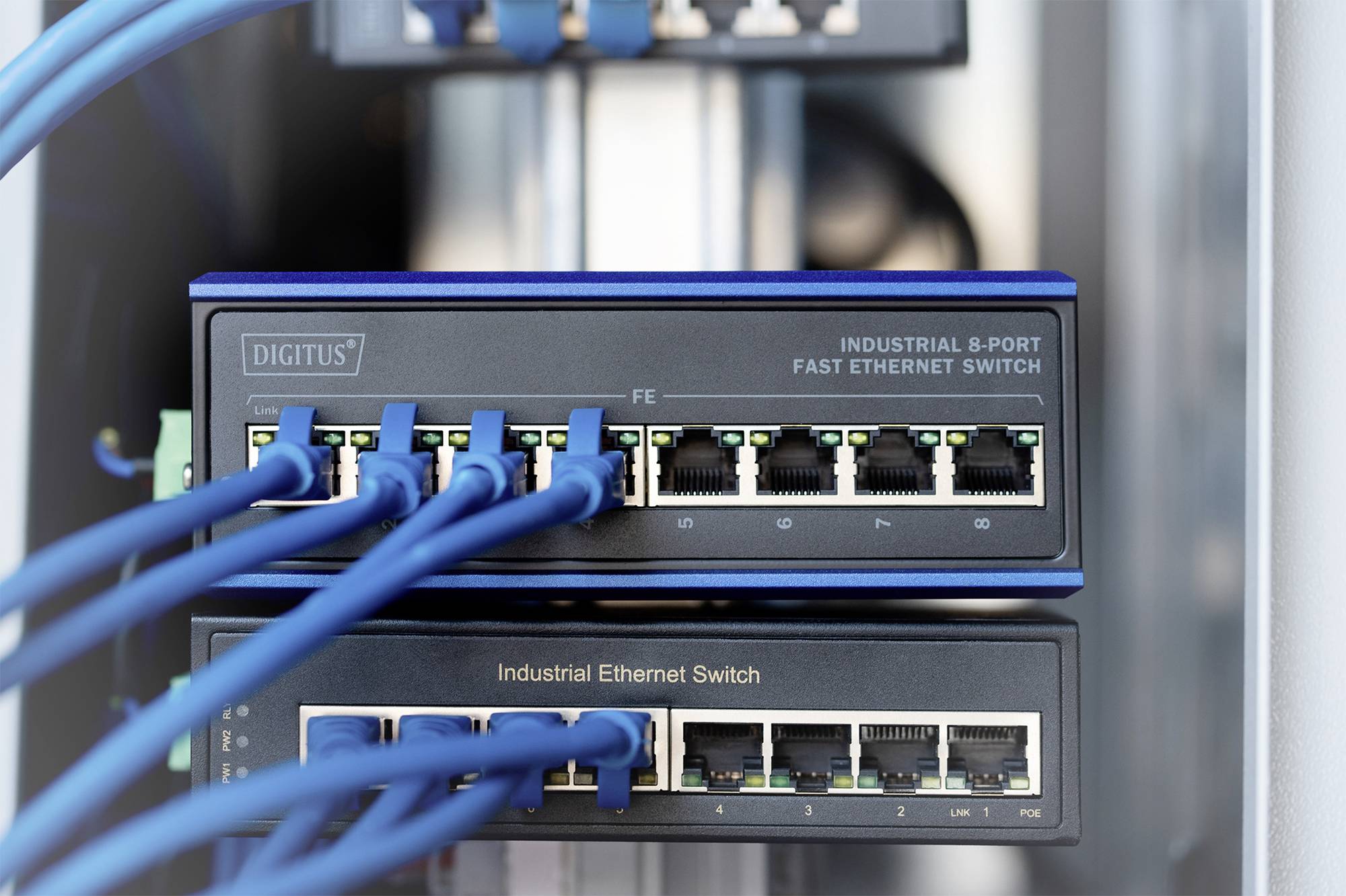 Two network switches with multiple inserted Ethernet cables; the upper switch is an 8-port Fast Ethernet switch, the lower one an Industrial Ethernet switch.