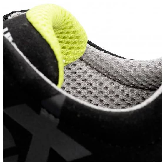 Close-up of the inner lining of a black sports shoe with a neon yellow accent and grey mesh fabric.
