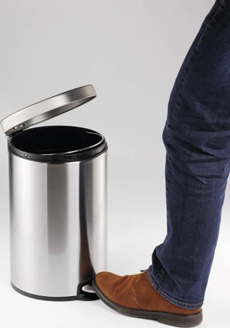 A person presses down on the pedal of a silver rubbish bin, whose lid is open.