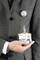 A person in a suit is holding a name badge in their hand. The badge is attached with a clip to the lapel.