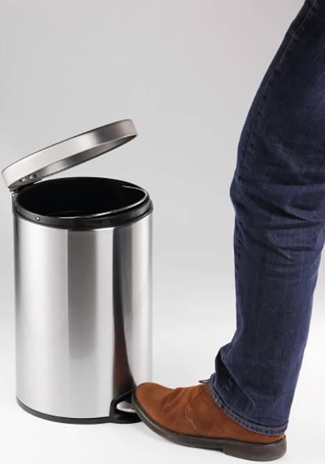 A person steps on the pedal of an open silver bin with their shoe.