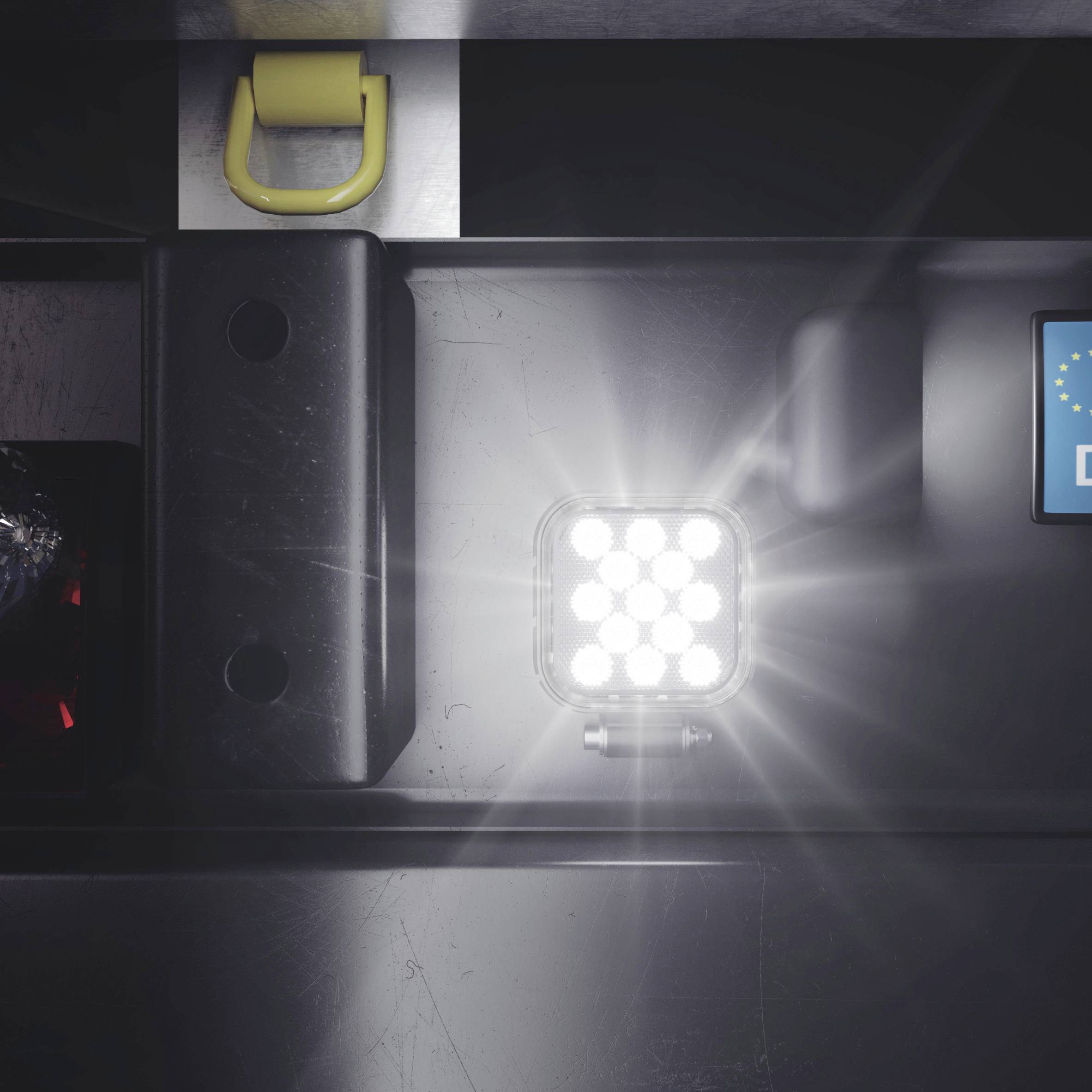 A bright LED light shines on a dark metal surface. Beside it is a sign with the European star symbol.