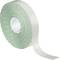Large roll of white adhesive tape with green squares, partially unrolled.