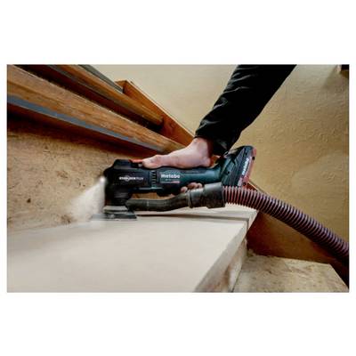 A person uses a hand-held electric sander to smooth the edge of a wooden step, with a vacuum hose for dust extraction.