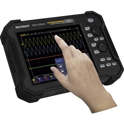 A person is operating a portable oscilloscope, model VOLTCRAFT DSO-5104H, with a touchscreen. Waveforms are visible on the display.