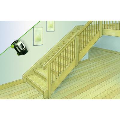 A robotic vacuum cleaner is climbing a wall next to a wooden staircase. Two pictures are hanging on the wall.