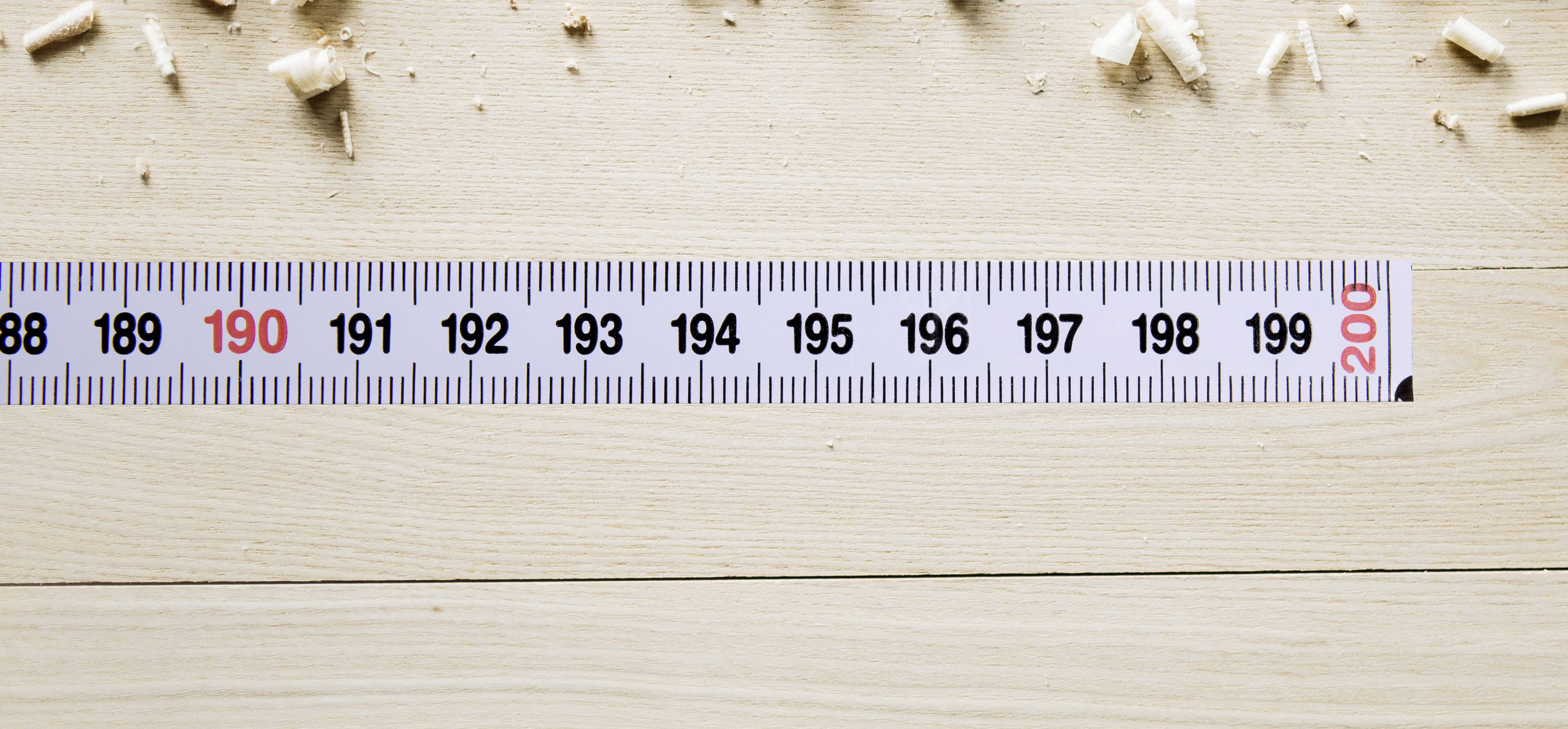 'Tape measure on a wooden surface with wood shavings on top. Marking shows 200 cm.'