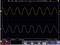 'Oscilloscope display with two sinusoidal waves: yellow above, blue below. Both waves show identical frequency at 5.00V.'