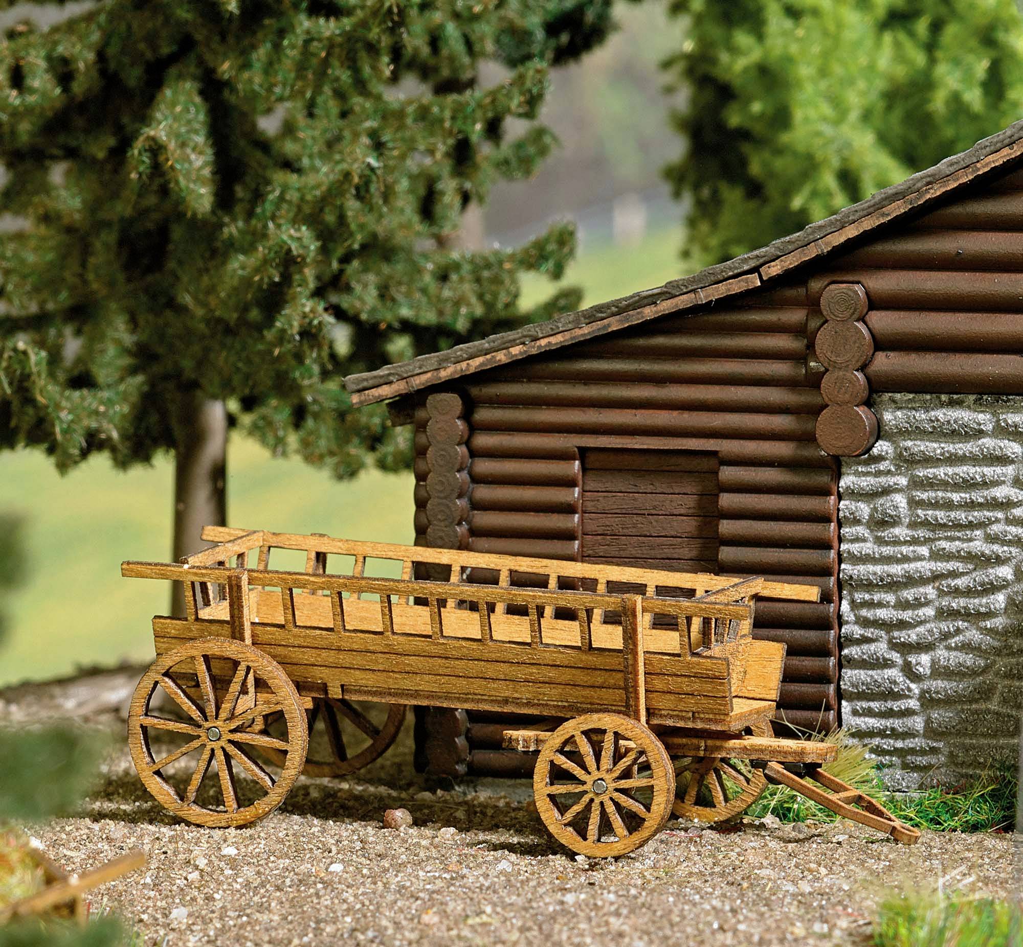 Wooden wagon in front of a log cabin in a wooded setting. The wagon is rustic and complements the rural scenery.