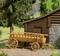Wooden wagon in front of a log cabin in a wooded setting. The wagon is rustic and complements the rural scenery.