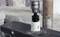 Drill with hole saw drilling a hole in a metal piece. Metal shavings are scattered around the hole. Background blurred.
