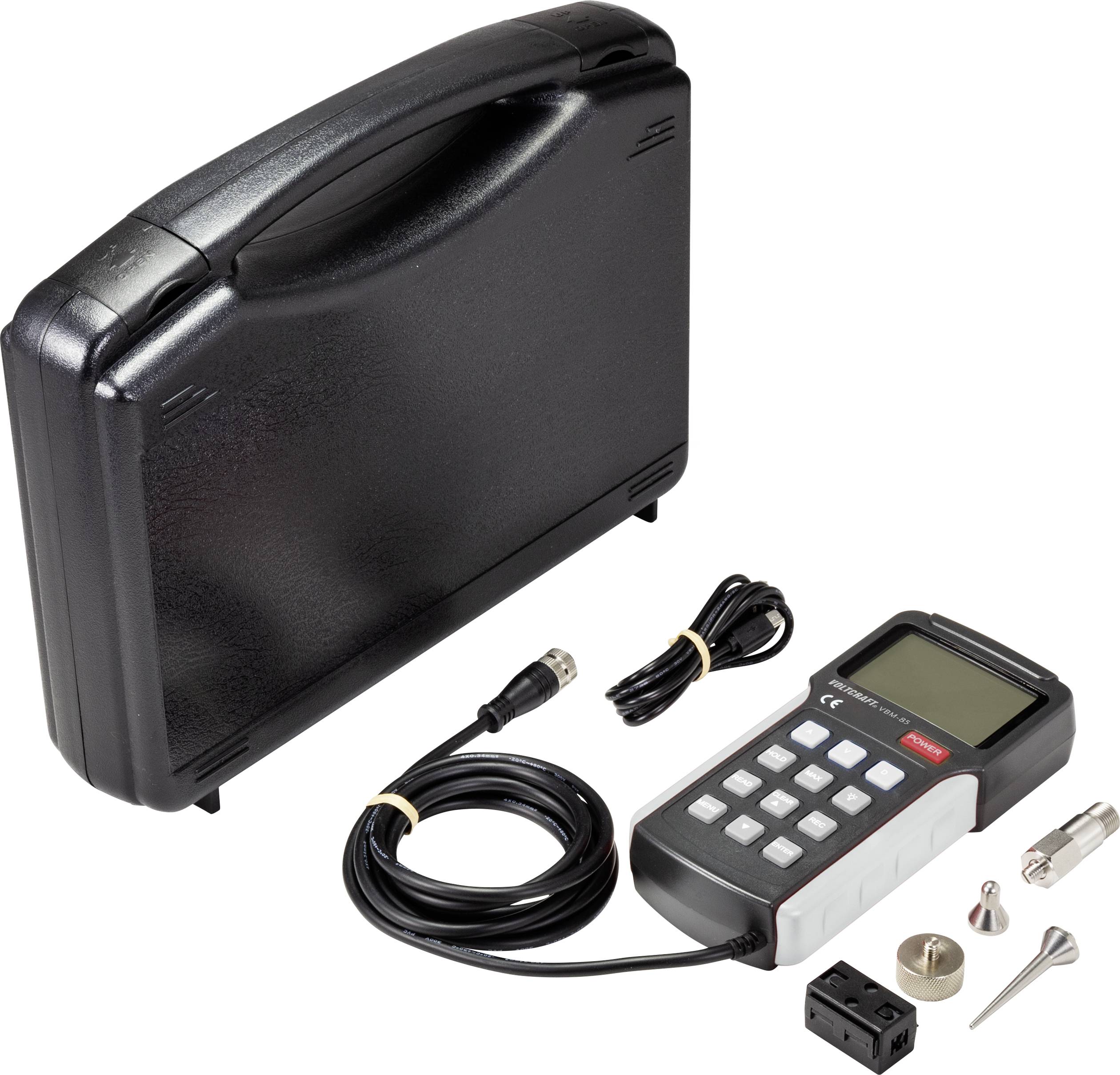 A digital measuring device with cables and accessories next to a black case.